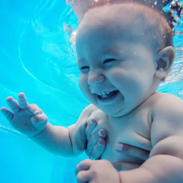 Ein lachendes Baby unter Wasser beim Babyschwimmen in der Donautherme Ingolstadt