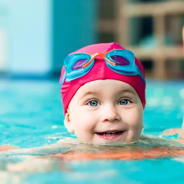 Ein fröhliches Kleinkind auf einer Schwimmnudel im Wasser beim Bambinischwimmen in der Donautherme Ingolstadt