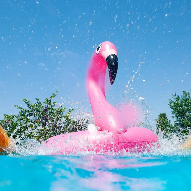 Ein aufblasbarer Flamingo und Schwimmringe im Wasser mit Spritzern